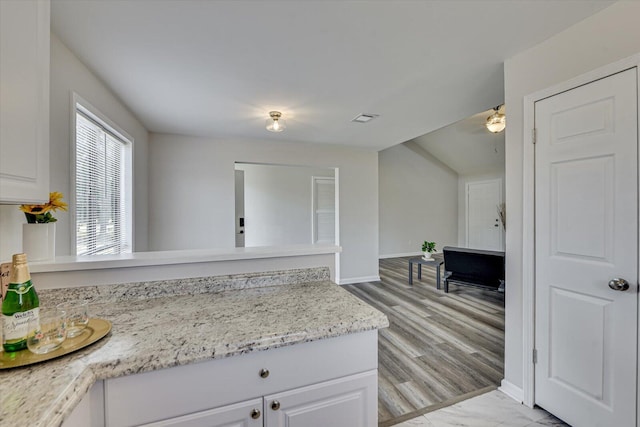 kitchen with white cabinetry, a peninsula, baseboards, and visible vents