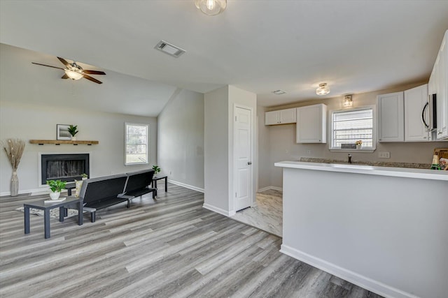 kitchen with white cabinetry, stainless steel microwave, a fireplace, and visible vents