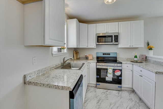 kitchen featuring marble finish floor, a sink, appliances with stainless steel finishes, white cabinets, and light countertops