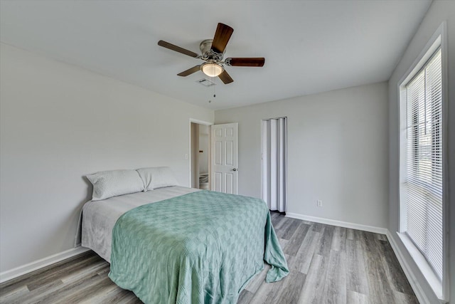 bedroom with visible vents, baseboards, wood finished floors, and a ceiling fan