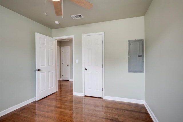 unfurnished bedroom with electric panel, ceiling fan, and hardwood / wood-style flooring