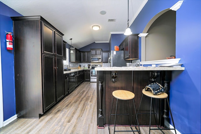 kitchen with pendant lighting, a breakfast bar, decorative backsplash, and appliances with stainless steel finishes