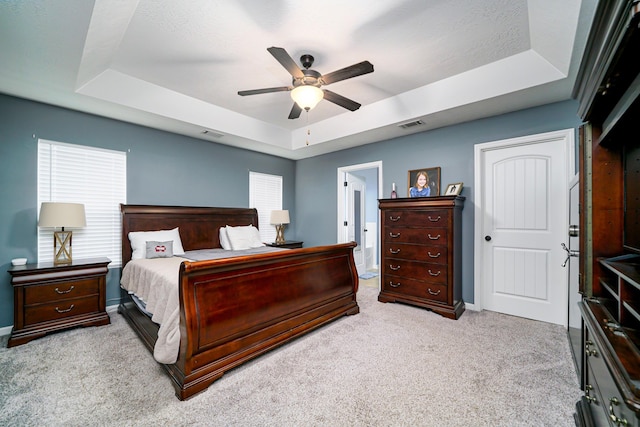 carpeted bedroom with a raised ceiling, ceiling fan, and a textured ceiling