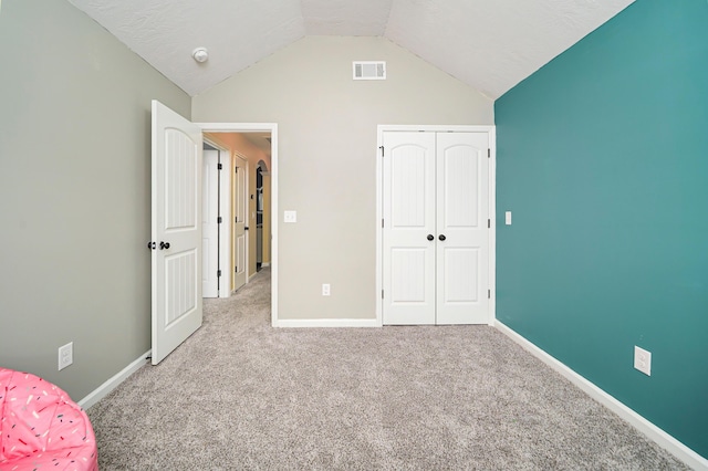 unfurnished bedroom with light carpet, vaulted ceiling, and a closet