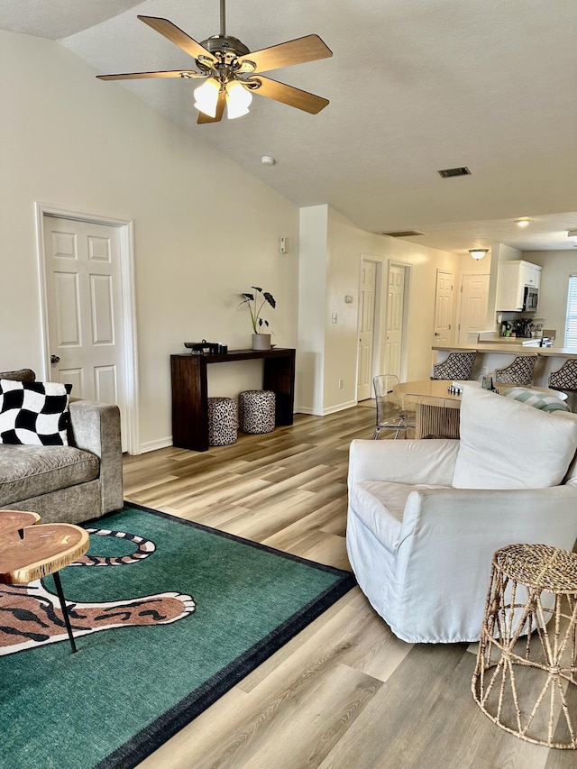 living room with lofted ceiling, light hardwood / wood-style floors, and ceiling fan