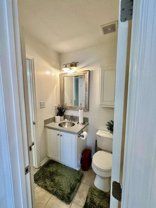 bathroom featuring vanity, tile patterned flooring, a textured ceiling, and toilet