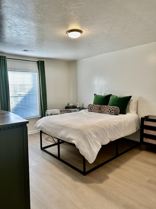 bedroom with a textured ceiling and light wood-type flooring