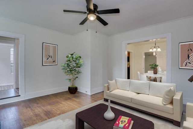 living room with hardwood / wood-style floors, ceiling fan with notable chandelier, and ornamental molding