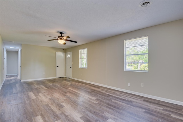 unfurnished room featuring a textured ceiling, ceiling fan, wood finished floors, and baseboards
