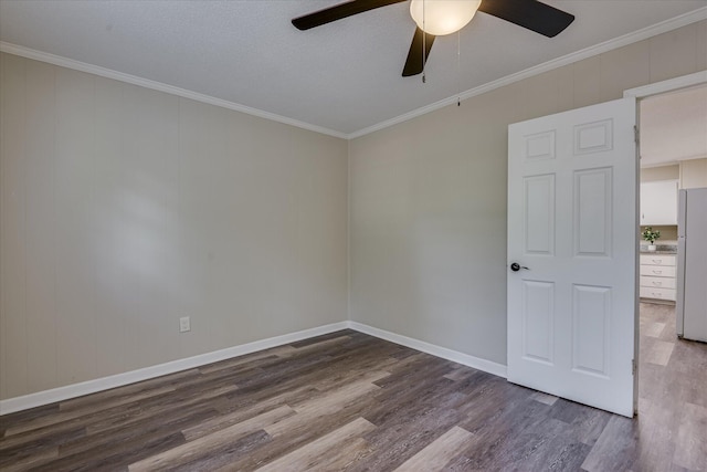 spare room with baseboards, wood finished floors, a ceiling fan, and crown molding