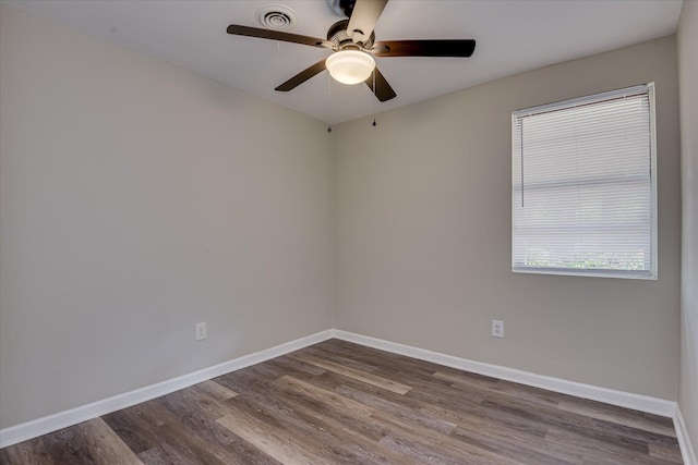 empty room with a ceiling fan, visible vents, baseboards, and dark wood-type flooring