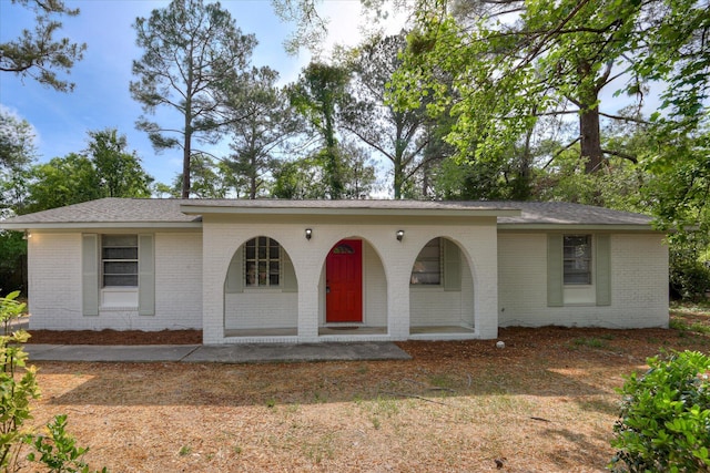 view of front of property featuring covered porch, brick siding, and a shingled roof