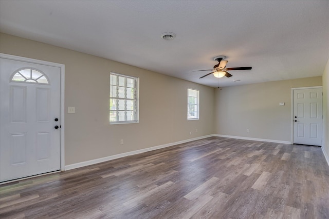 foyer entrance with visible vents, ceiling fan, wood finished floors, and baseboards