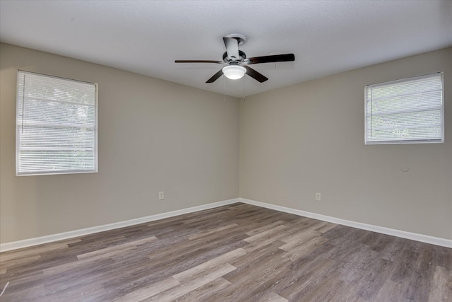 empty room with baseboards, wood finished floors, and ceiling fan