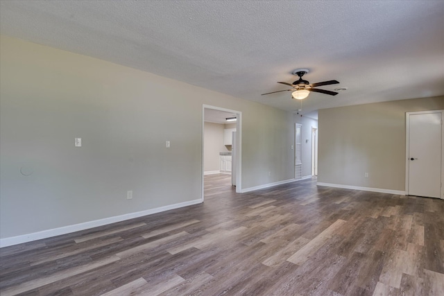 unfurnished room with a textured ceiling, ceiling fan, baseboards, and dark wood-type flooring