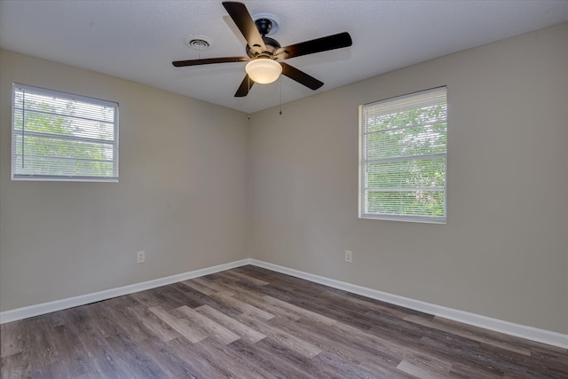 unfurnished room featuring baseboards, visible vents, wood finished floors, and a ceiling fan