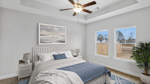 bedroom with carpet, a tray ceiling, visible vents, and baseboards