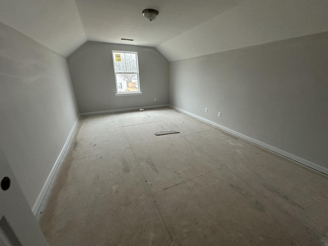 additional living space featuring lofted ceiling, visible vents, and baseboards