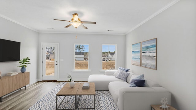 living room with a ceiling fan, wood finished floors, baseboards, visible vents, and crown molding