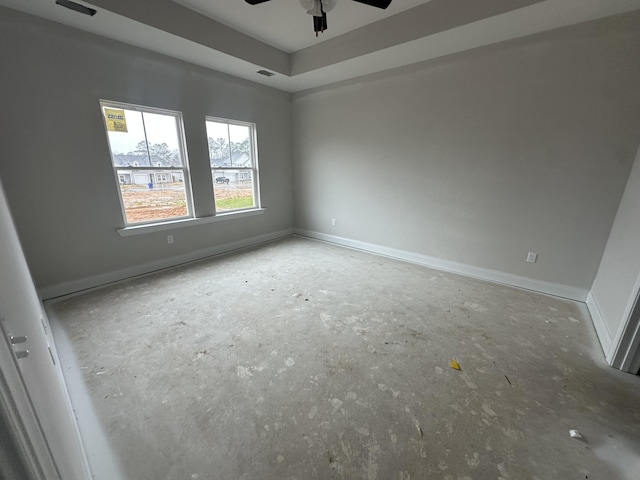 spare room with visible vents, a ceiling fan, a raised ceiling, and baseboards