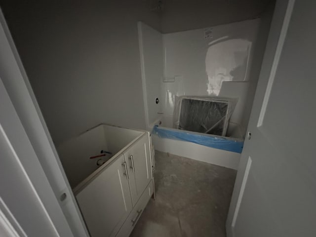 bathroom featuring unfinished concrete floors, a bath, and vanity