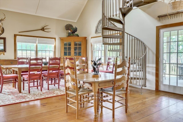 dining room with light wood-style flooring and high vaulted ceiling