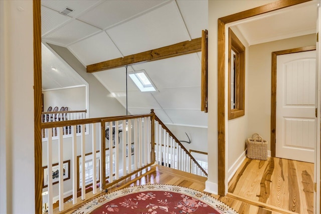 stairs featuring lofted ceiling with skylight, visible vents, baseboards, and wood finished floors