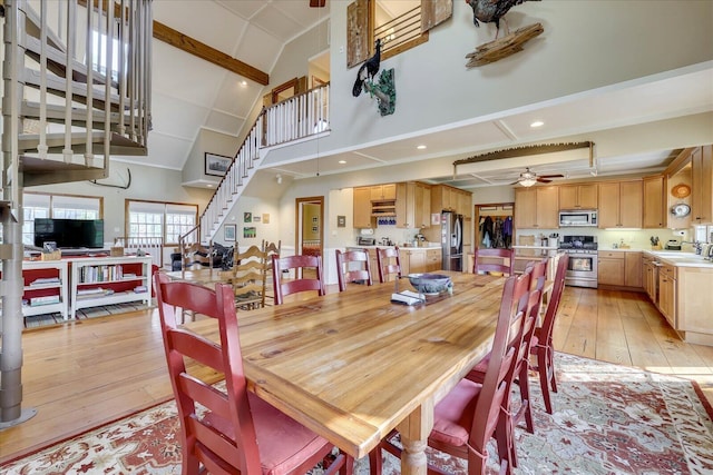 dining space with ceiling fan, stairs, light wood-type flooring, recessed lighting, and a high ceiling
