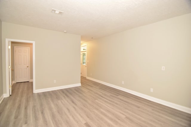 unfurnished room with a textured ceiling and light wood-type flooring