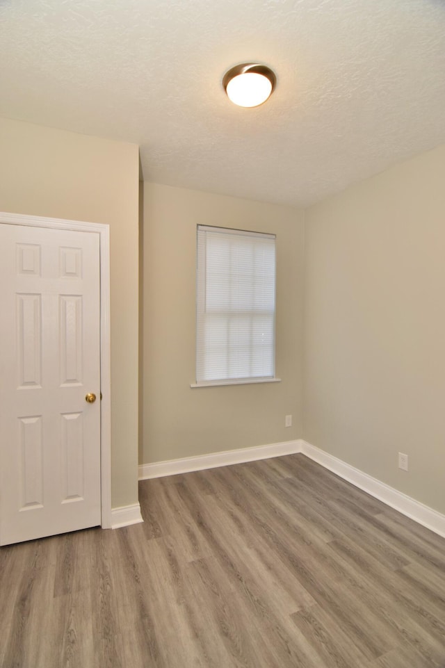 empty room with hardwood / wood-style floors and a textured ceiling