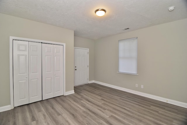 unfurnished bedroom with a closet, wood-type flooring, and a textured ceiling