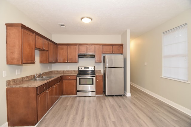 kitchen featuring a textured ceiling, light wood-type flooring, sink, and appliances with stainless steel finishes