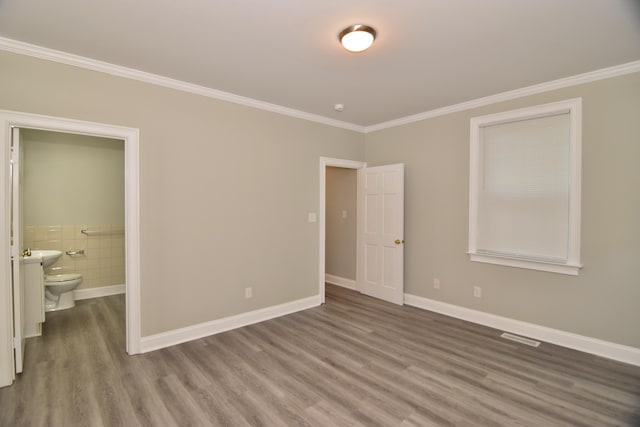 unfurnished bedroom with connected bathroom, hardwood / wood-style flooring, and ornamental molding