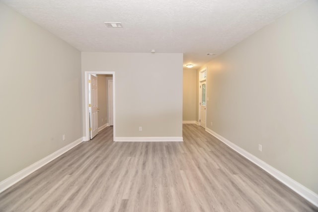 empty room with a textured ceiling and light wood-type flooring