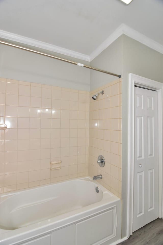 bathroom featuring tiled shower / bath combo, wood-type flooring, and ornamental molding