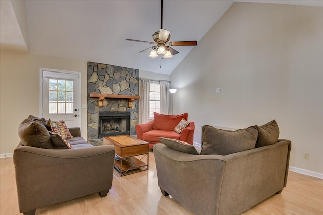 living room featuring a fireplace, light wood-type flooring, high vaulted ceiling, and ceiling fan