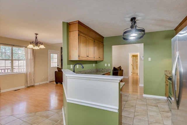 kitchen featuring a textured ceiling, stainless steel appliances, light tile patterned floors, decorative light fixtures, and an inviting chandelier