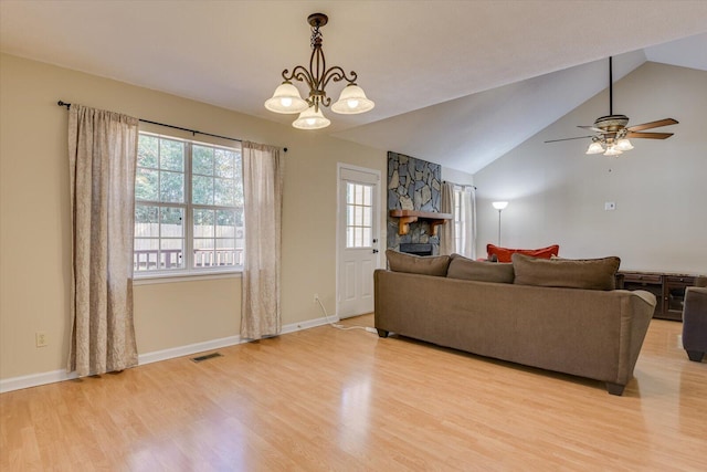 living room featuring ceiling fan with notable chandelier, light hardwood / wood-style floors, lofted ceiling, and a fireplace