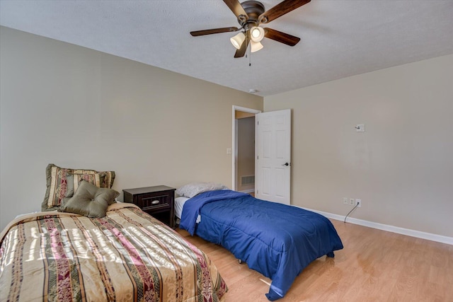 bedroom with a textured ceiling, light hardwood / wood-style floors, and ceiling fan