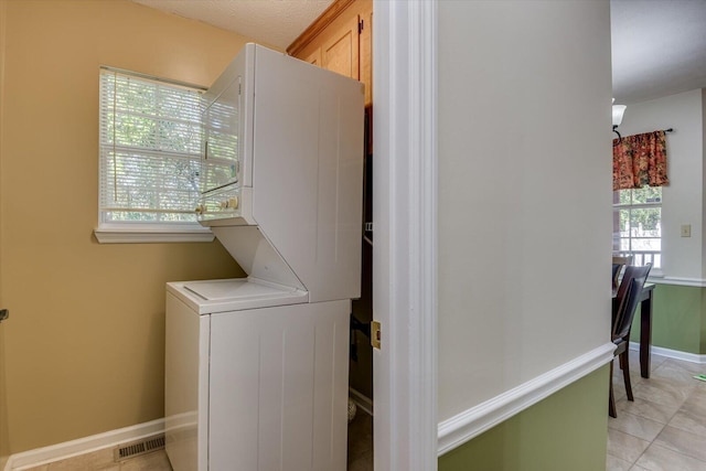 laundry room featuring stacked washer / dryer and light tile patterned flooring