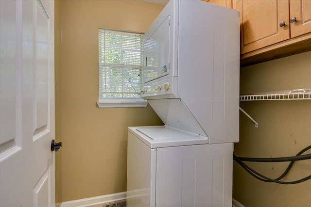 laundry room featuring cabinets and stacked washer / drying machine