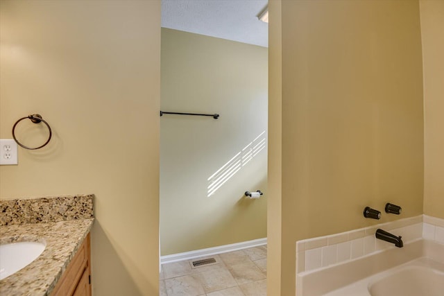 bathroom featuring a textured ceiling, vanity, and a bath