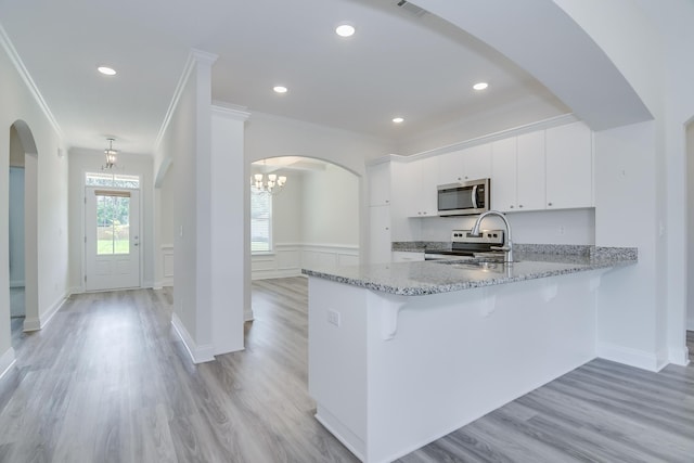326 Agape Ln, Trenton, SC 29847 - kitchen featuring appliances with stainless steel finishes, ornamental molding, light wood-style floors, a kitchen bar, and a peninsula