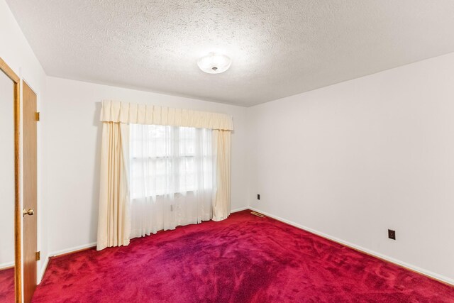 spare room featuring carpet floors and a textured ceiling