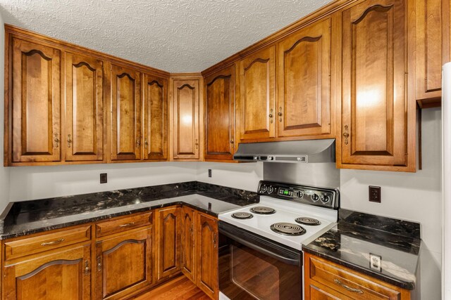 kitchen featuring dark stone countertops, light wood-type flooring, a textured ceiling, and white electric range