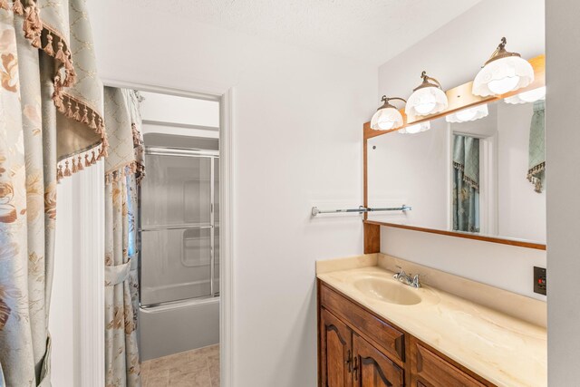 bathroom featuring shower / bath combination with glass door, a textured ceiling, and vanity