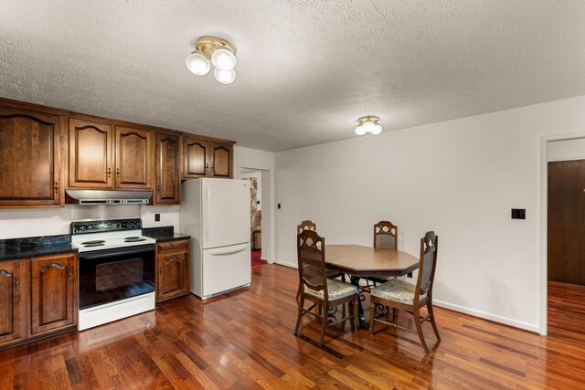 kitchen featuring a textured ceiling, white appliances, and dark wood-type flooring