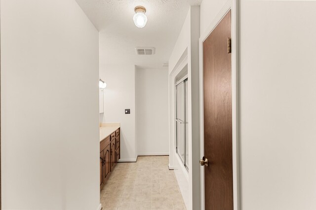 bathroom with vanity, a textured ceiling, and walk in shower