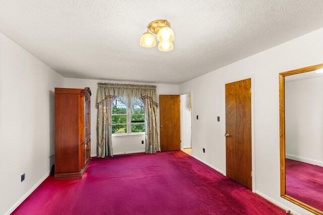 unfurnished bedroom with a textured ceiling and dark colored carpet