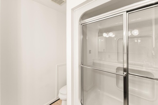 bathroom with toilet, tile patterned floors, and walk in shower